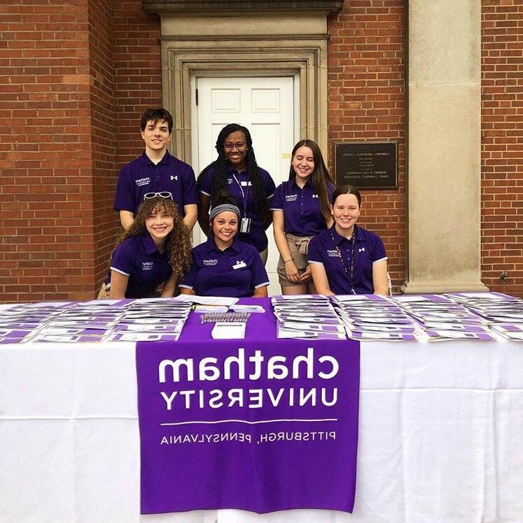 Photo of six Chatham University students in purple shirts, working at a table outside on 欧洲杯官方投注网站